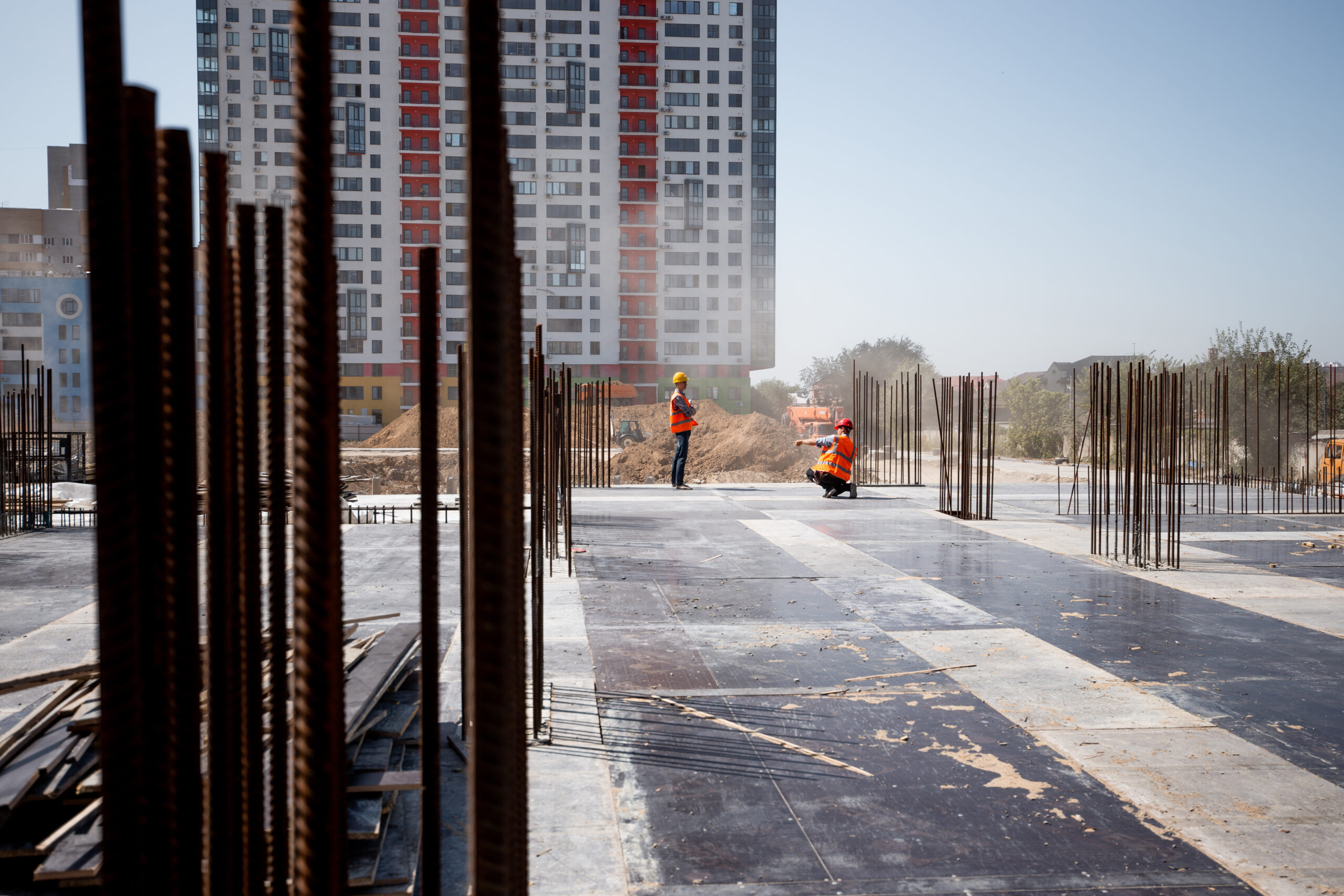 The building site against the background of a multistorey building. Two builders are working .