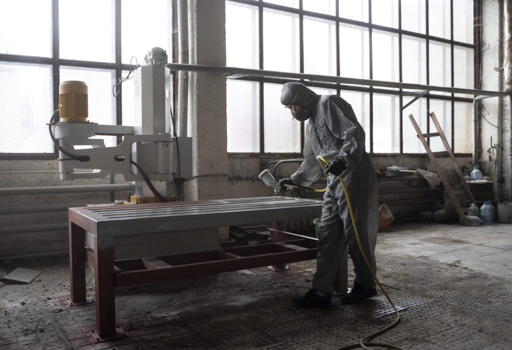 man-spraying-powder-paint-from-gun-full-shot-min