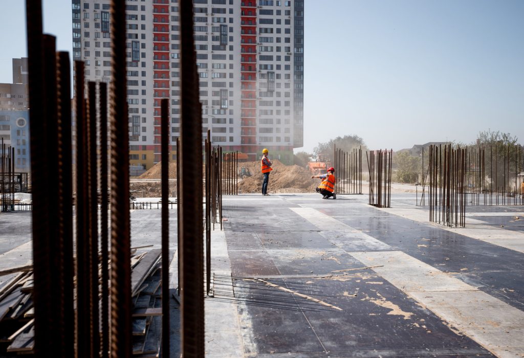 The building site against the background of a multistorey building. Two builders are working .